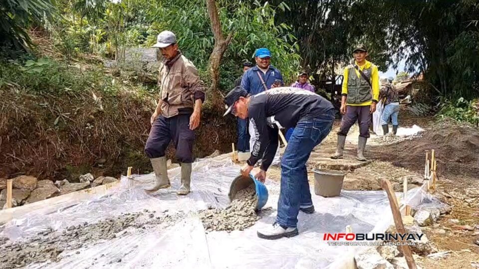 Pekerja bersama aparat desa menuangkan adukan rabat beton pada pembangunan jalan desa di Kampung Pasirawi, Kecamatan Ciwidey.