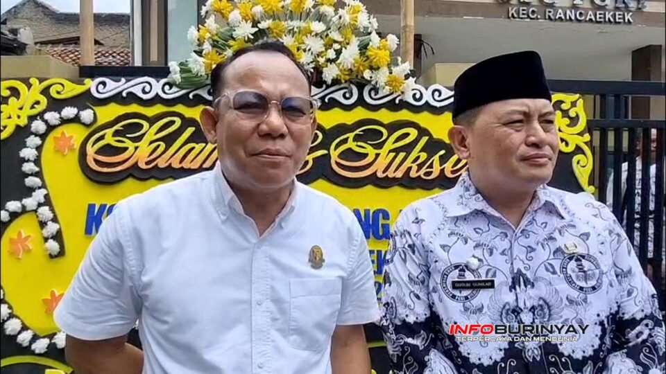 Seorang pejabat legislatif Kabupaten Bandung bersama Plt Camat Rancaekek berdiri di depan papan ucapan selamat pada kegiatan Konferensi Cabang PGRI Rancaekek ke-23