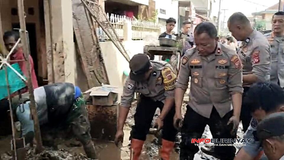 Petugas kepolisian bersama warga membersihkan lumpur sisa banjir di permukiman RW 01 Desa Bojong, Majalaya, Kabupaten Bandung.