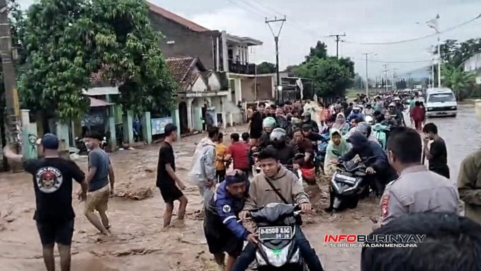 Warga dan pengendara melintasi jalan berlumpur akibat banjir dari jebolnya tanggul Sungai Cisunggalah di Majalaya