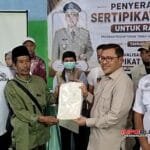 Anggota DPR RI Dr. H. Ahmad Heryawan, Lc., M.Si. menyerahkan sertifikat tanah Program PTSL Tahun 2026 kepada warga pada kegiatan penyerahan sertifikat dan sosialisasi Sertifikat Elektronik di GOR Desa Drawati, Kecamatan Paseh, Kabupaten Bandung.